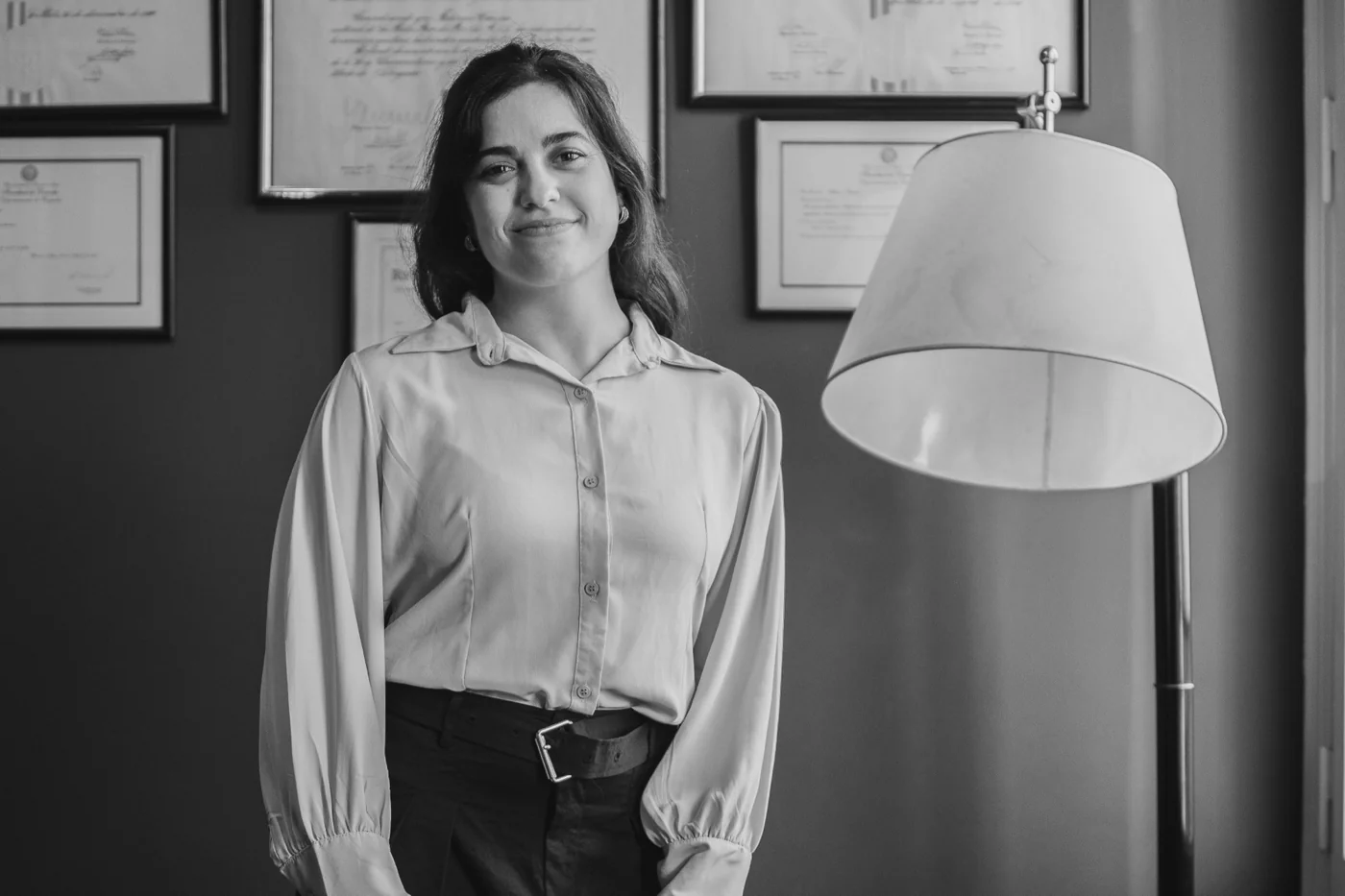 Retrato en blanco y negro de Eliana García frente a sus diplomas universitarios